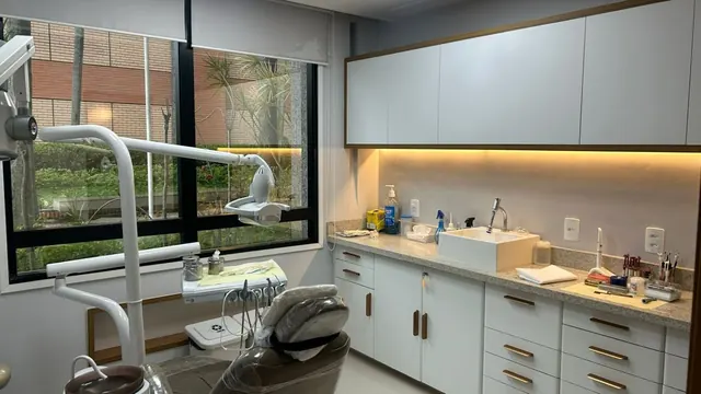 Consultório odontológico com cadeira, bancada e janela na Barra da Tijuca