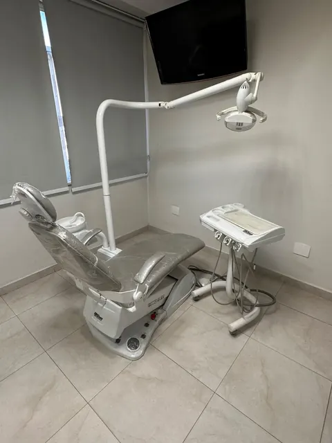 Consultório odontológico com cadeira clara e equipamentos em Vila Valqueire