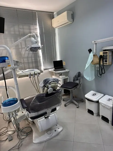 Consultório odontológico com cadeira escura e equipamentos em Vila Valqueire